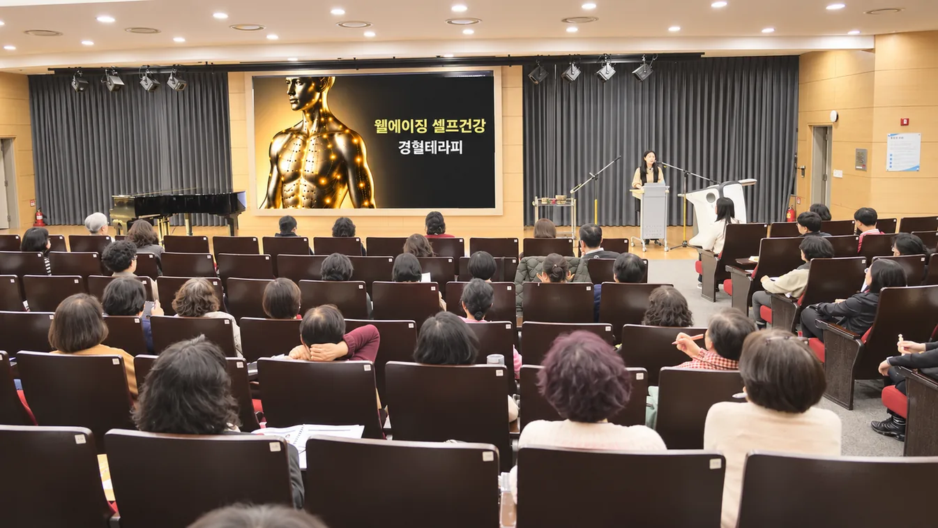 강당의 참가자들이 화면을 보며 건강강의를 듣는 모습